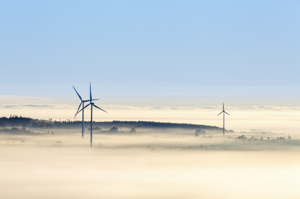 Vindkraftverk i dimmigt sydsvenskt landskap.